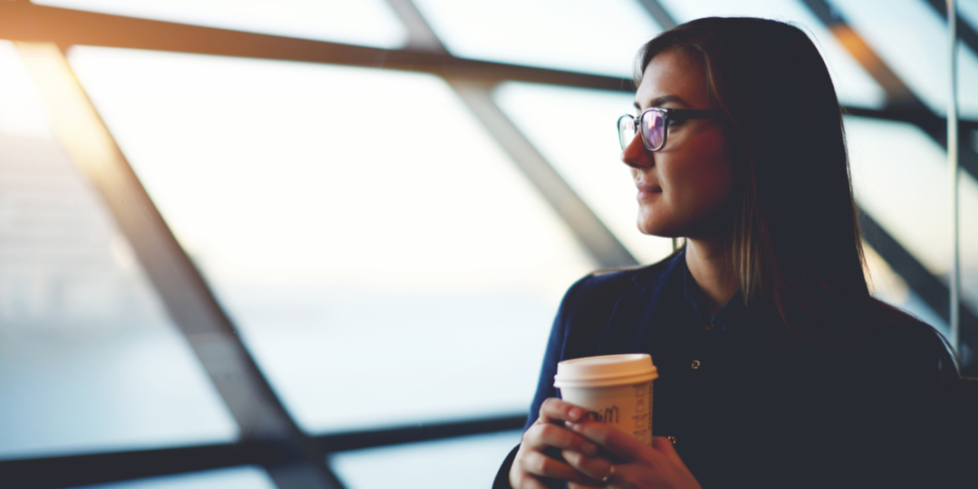 girl sitting near big window with coffee take away in airport