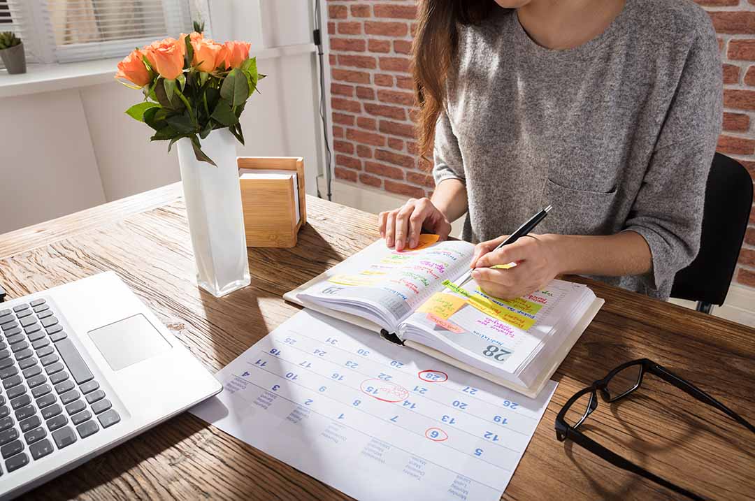 Image of a professional planner marking dates in an agenda, here are some tips on how to plan an event.