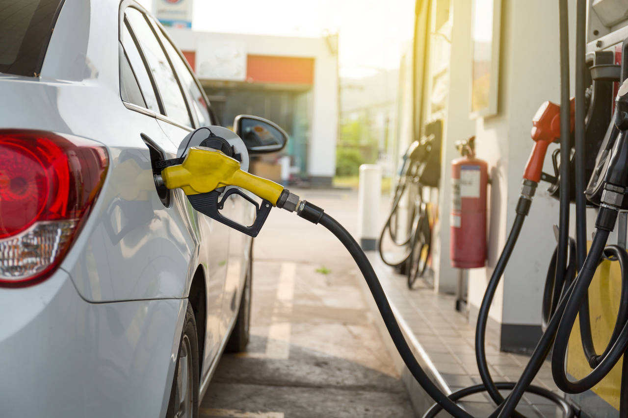 Transportation and ownership concept - woman pumping gasoline fuel in car at gas station during Russia-Ukraine war that oil or gasohol price high. 