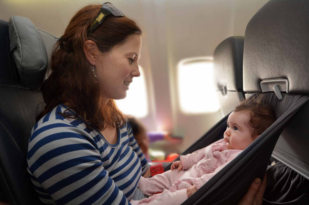 Image of a new mom on a plane,here are some tips for smooth travel with baby.