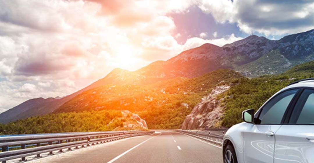 car driving towards sunset