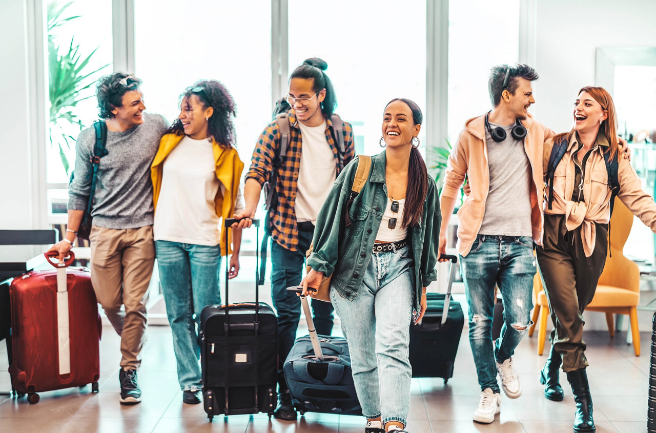 Young group of tourists with suitcases arriving at youth hostel guest house - Happy friends enjoying summer vacation together - Millenial people doing check-in at hotel lobby - Summertime holidays