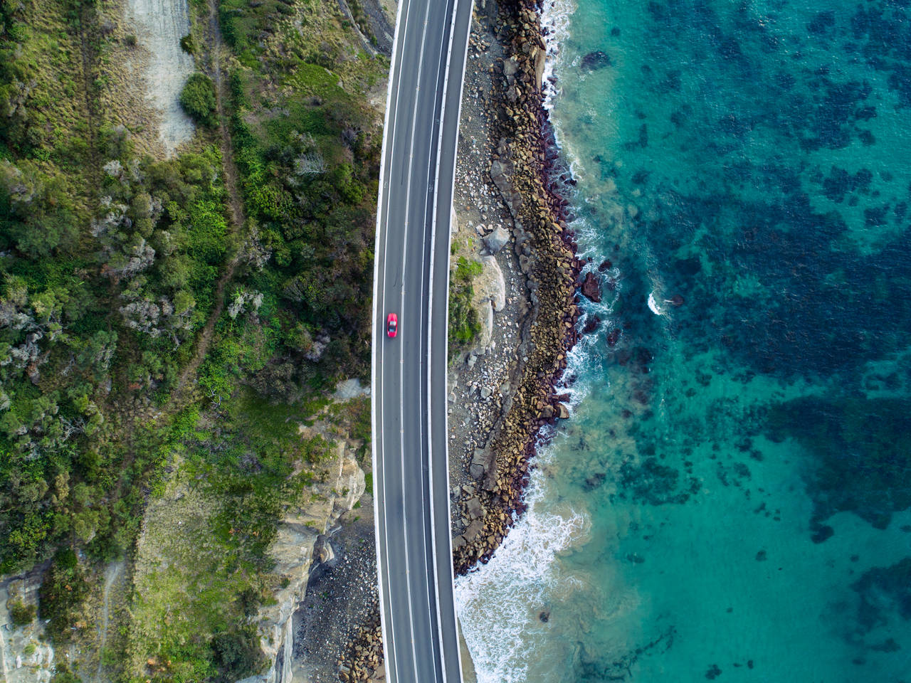 Aerial photograph of a car driving through the Sea Cliff Bridge, New South Wales