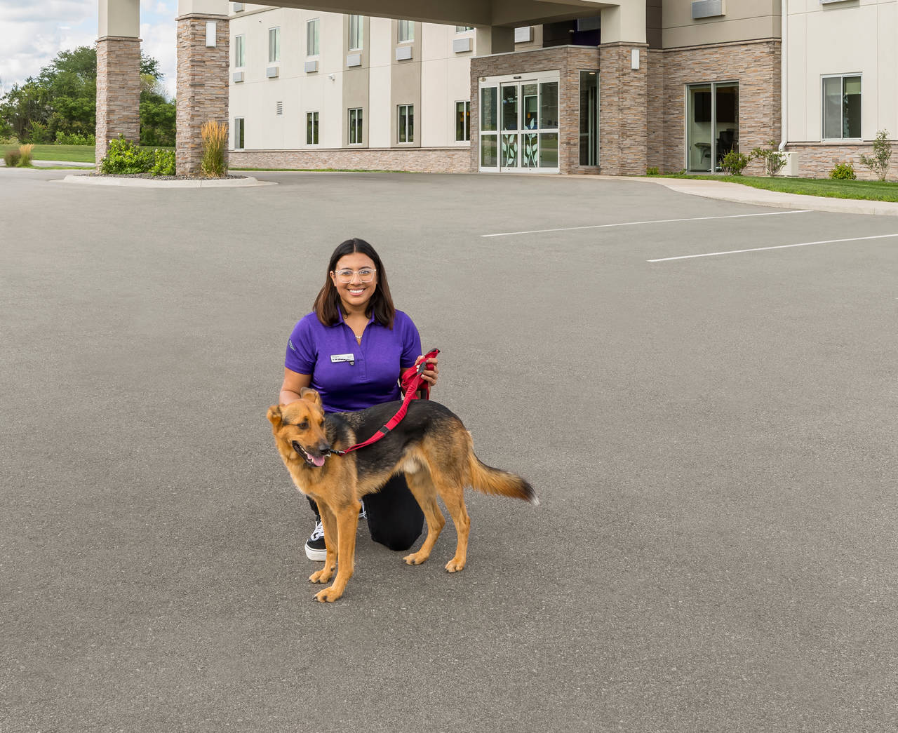 Hotel employee and dog in front of dog friendly Sleep Inn hotel