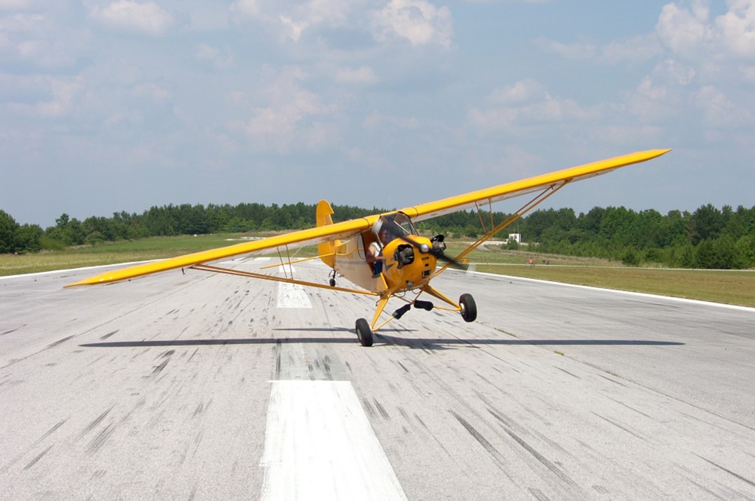 A yellow biplane touches a wheel to the runway at one of the best air shows in the U.S.